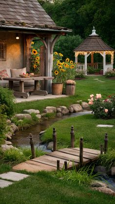 a gazebo sitting next to a small stream in the grass with flowers on it