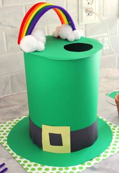 a green hat with a rainbow on top and clouds in the middle, sitting on a table