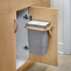 a trash can is in the corner of a cabinet