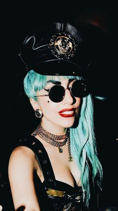 a woman with blue hair wearing a hat and sunglasses