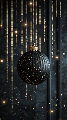 a black ornament hanging from a string with gold lights in the back ground