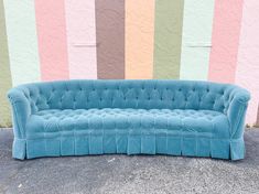 a blue couch sitting in front of a wall with multicolored stripes on it