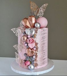 a three tiered cake decorated with pink and silver decorations