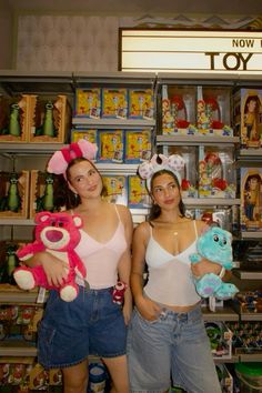 two young women holding stuffed animals in front of toys