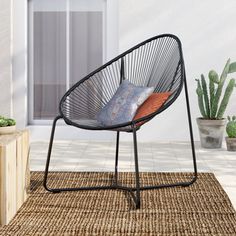 a black chair sitting on top of a rug next to a potted cacti