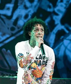 a man with green paint on his face holding a microphone in front of a stage