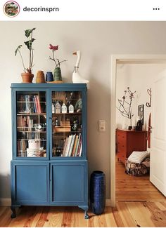 a blue cabinet with books and vases on top in a living room next to a door