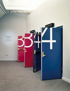 the doors are all different colors and numbers in this room with carpeting on the floor