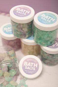 bath salts in small jars on a table next to a jar filled with green and white candies