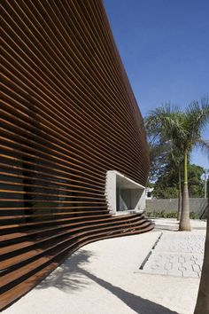 a building with wooden slats on the side and palm trees in the foreground