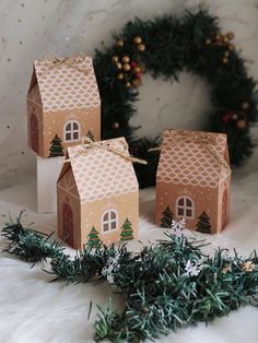 three small houses are sitting next to a wreath on a white furnishing covered floor