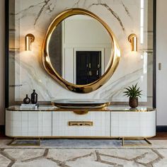 a large round mirror sitting on top of a white cabinet next to a potted plant