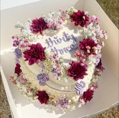 a birthday cake decorated with flowers in a box