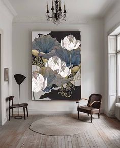 a painting hanging on the wall above a chair in a room with wooden floors and white walls