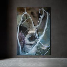 an abstract painting on the wall in a room with concrete flooring and gray walls