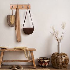 a wooden bench sitting in front of a white wall next to a potted plant