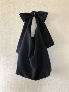 a black bag hanging on the wall with a bow tie around it's neck