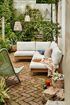 an outdoor living area with couches, chairs and potted plants in the background