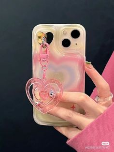 a person holding up a phone case with a heart charm