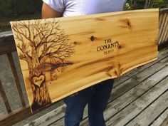 a person holding up a wooden sign with a tree on it