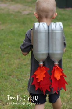 a young boy holding two silver cups with red leaves on them