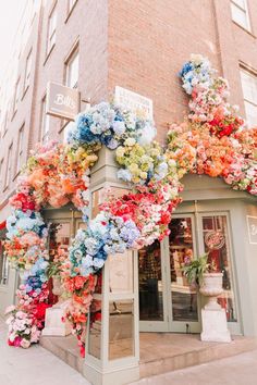 a building with flowers all over the front and side of it's windows on display