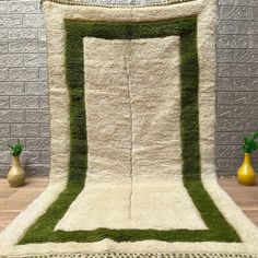 a green and white area rug sitting on top of a wooden floor next to vases