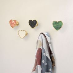 three heart shaped brooches hang on the wall next to a towel and two ear clips