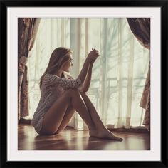 a woman sitting on the floor in front of a window