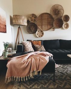 a living room filled with furniture and lots of baskets hanging on the wall above it