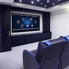 an empty home theater with blue seats and a flat screen tv mounted on the wall