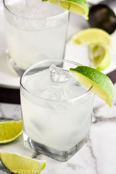 two glasses filled with ice and limes