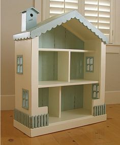 a toy doll house sitting on top of a hard wood floor next to a window