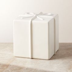 a white present box with a bow on the top is sitting on a marble surface