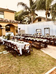 an outdoor dining area with tables and chairs set up for a formal function in front of a house