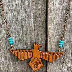 a wooden bird necklace with turquoise beads on it