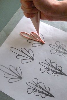 a person is drawing on paper with scissors and inking them into the shape of flowers