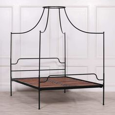 an iron bed frame with wooden slats on the bottom and foot board, against a white wall