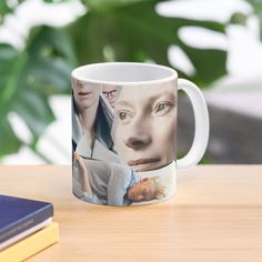 a coffee mug with the faces of two people on it and a book next to it