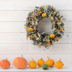 a wreath with pumpkins and other decorations around it