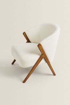 an upholstered chair with wooden legs and a white fabric cover on the back