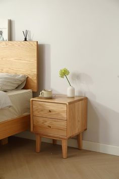 a bedroom with a bed, nightstand and flower pot on the end table next to it