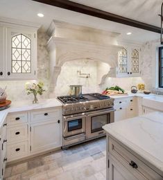 a large kitchen with white cabinets and marble counter tops is pictured in this image, there are two windows above the stove