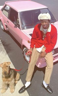 a man sitting on top of a pink car next to a brown dog with a leash