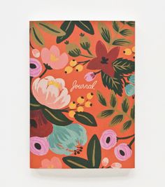 an orange notebook with flowers and leaves on the cover, in front of a white background