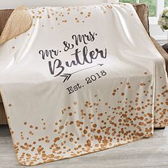 a white and gold wedding blanket sitting on top of a couch