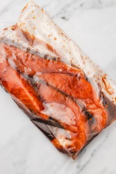 some kind of food wrapped in plastic on top of a marble countertop with brown and white stuff around it