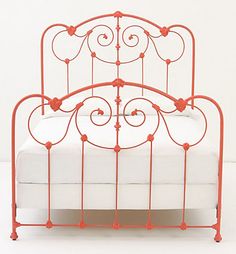 an orange iron bed frame with hearts on the headboard and foot board, against a white background