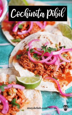 two tacos filled with meat, onions and cilantro on top of a blue table