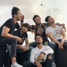 four young men are sitting on the back of a truck and posing for a photo